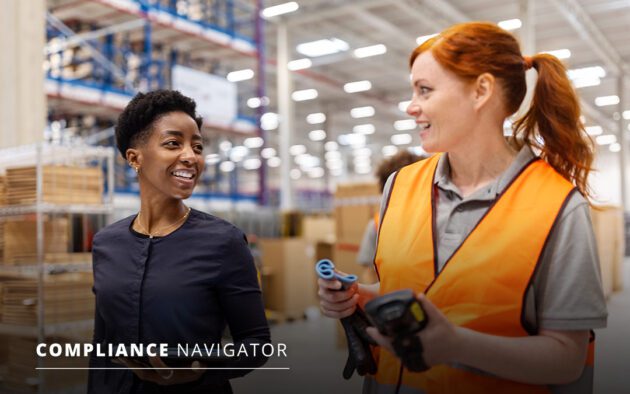 Two women talking in a warehouse. One is wearing a black shirt and the other an orange safety vest, holding tools. Text reads "Compliance Navigator.
