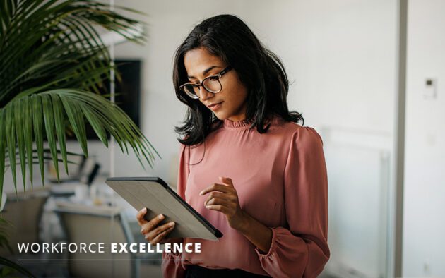 A woman in a pink blouse is standing and looking at a tablet. The words "Workforce Excellence" appear in the bottom left corner.